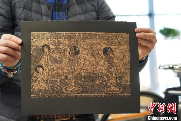 圖為手工書藝人展示敦煌雕版壁畫印刷品。　九美旦增 　攝