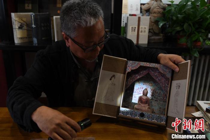 圖為讀者出版集團(tuán)讀者晉林工作室獨(dú)立出品人徐晉林，展示互動(dòng)性強(qiáng)的敦煌題材手工書。(資料圖) 楊艷敏 攝