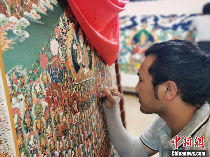 圖為更登才讓的徒弟繪畫(huà)唐卡?！?zhí)砀?攝